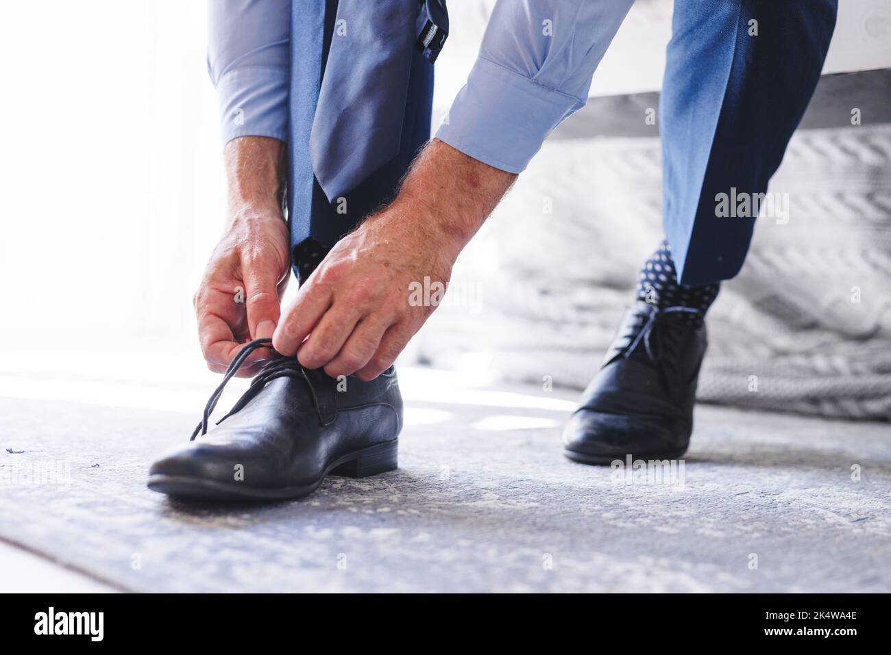 Midsection of caucasian man standing in bedroom, tying shoelaces Stock ...