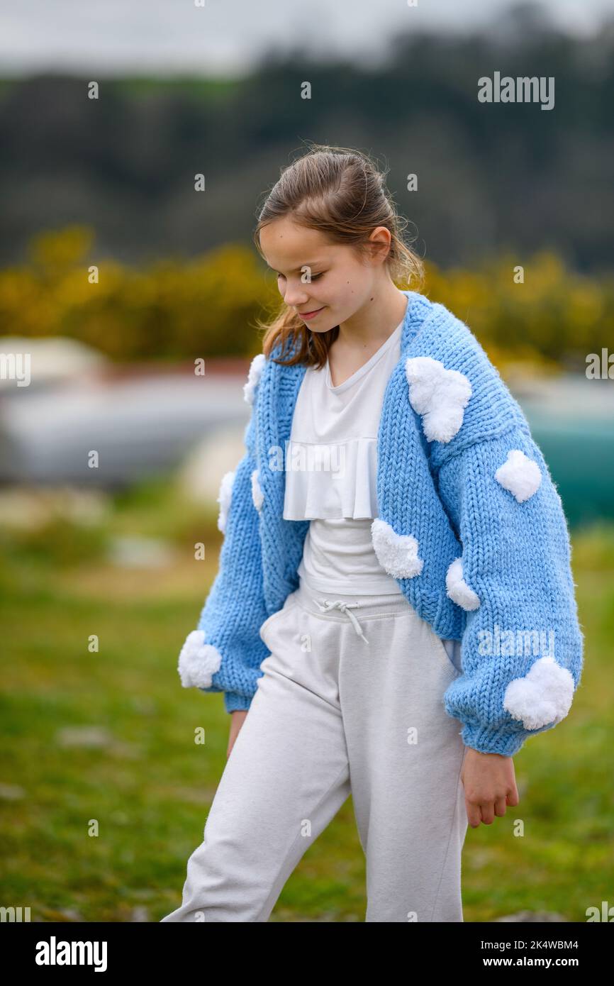 Smiling girl in a knitted cardigan walking outdoors Stock Photo