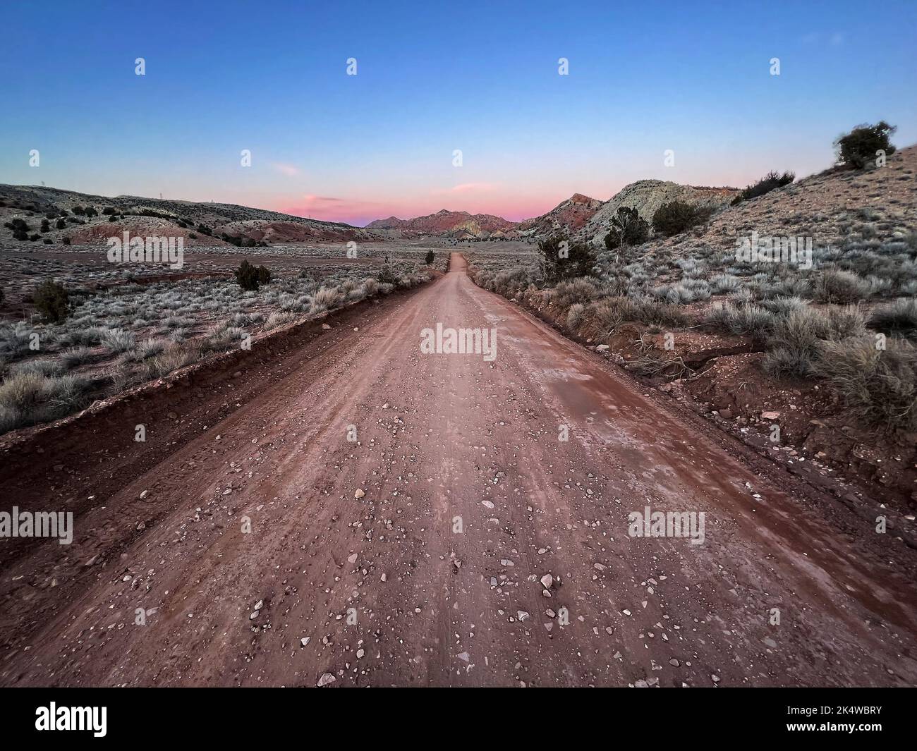 Straight dirt road through rural landscape at sunset near Vermilion Cliffs National Monument, Utah, USA Stock Photo