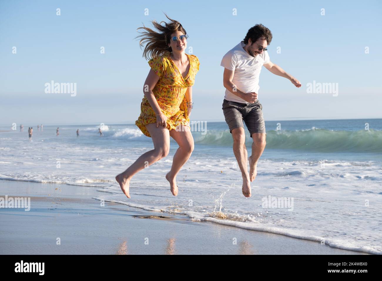 Happy couple jumping in the air on a beach in summer, France Stock Photo