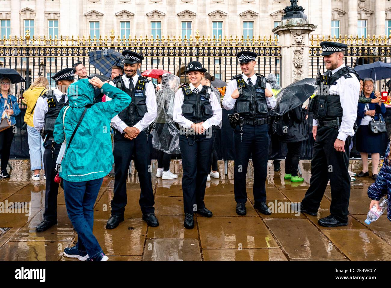 Metropolitan Police Officers Stand Outside Buckingham Palace In The Rain, London, UK. Stock Photo