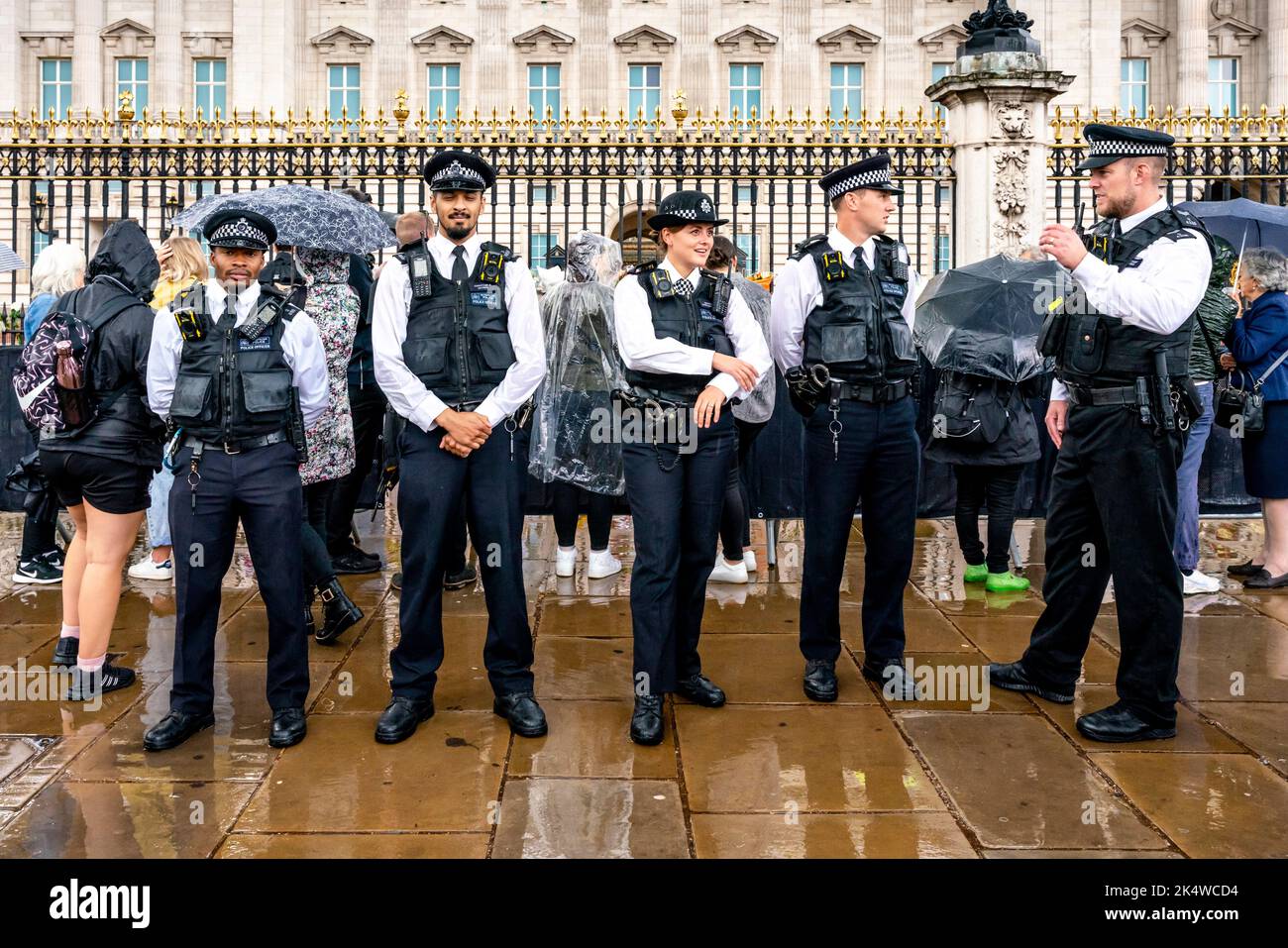 Metropolitan Police Officers Stand Outside Buckingham Palace In The Rain, London, UK. Stock Photo