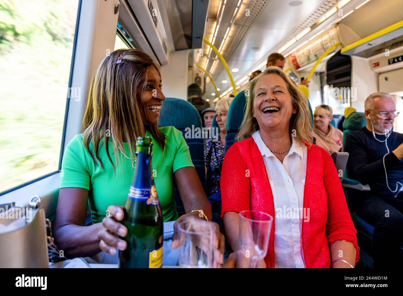 Two Mature Women Enjoy A Glass Of Prosecco On The Train, Sussex, UK. Stock Photo