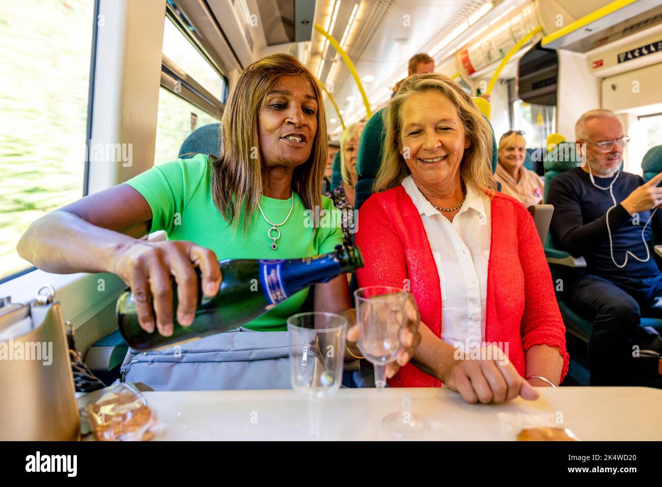 Two Mature Women Enjoy A Glass Of Prosecco On The Train, Sussex, UK. Stock Photo