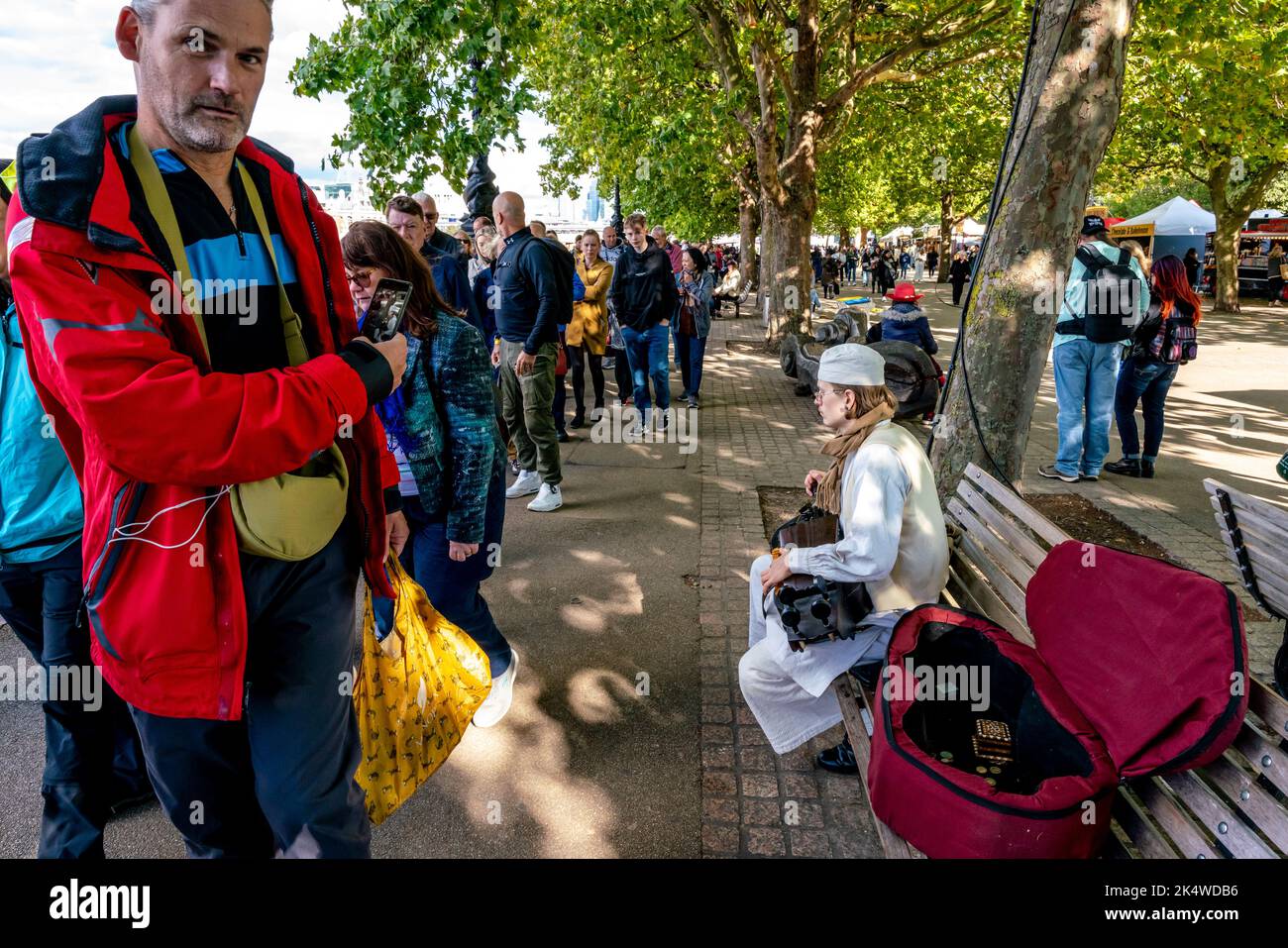 A Busker Entertains People Who are Queueing To See The Queen Lying-In-State At Westminster Hall, London, UK. Stock Photo