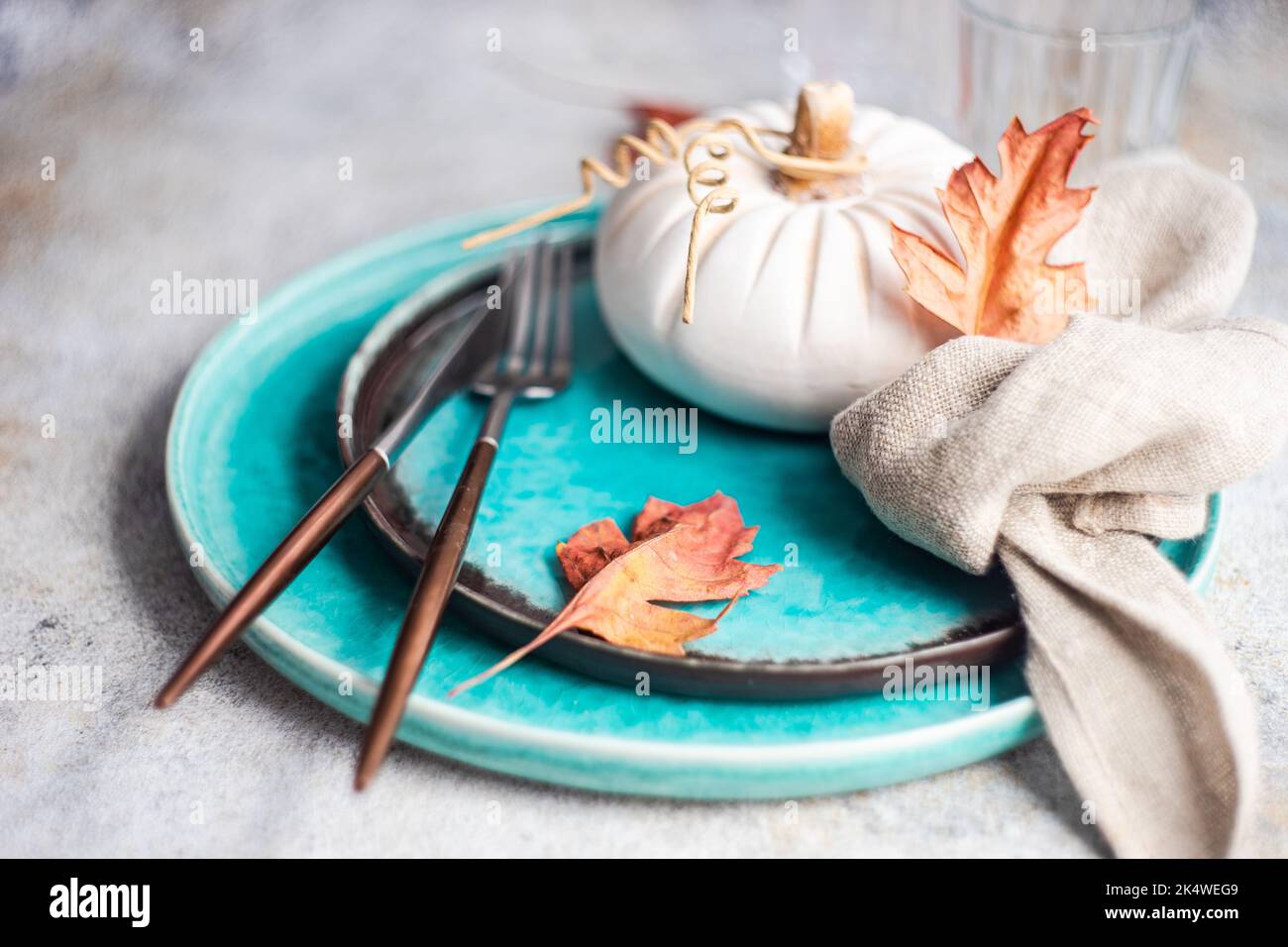 Autumnal place setting with a decorative ceramic pumpkin and autumn leaves Stock Photo