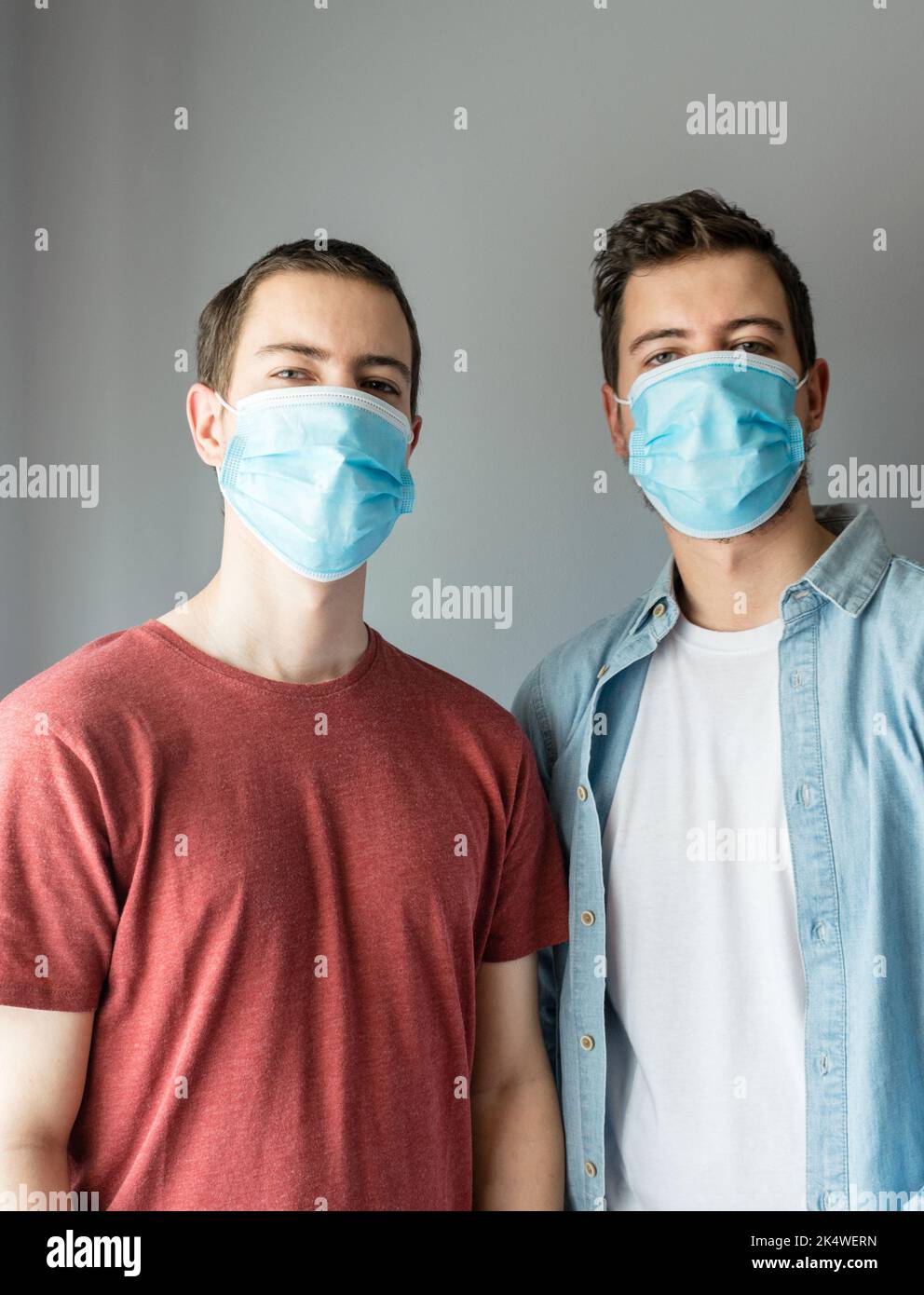Close-up portrait of two men standing side by side wearing disposable protective face mask Stock Photo