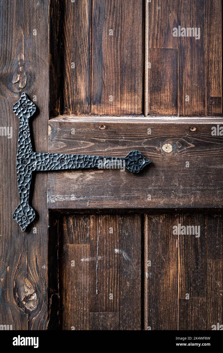 An old grungy, brown, natural wooden door part with grains and with black metal hinge, for background and texture. High quality photo Stock Photo