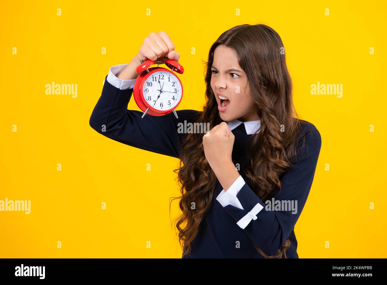 Teenager child hold clock isolated on yellow studio background