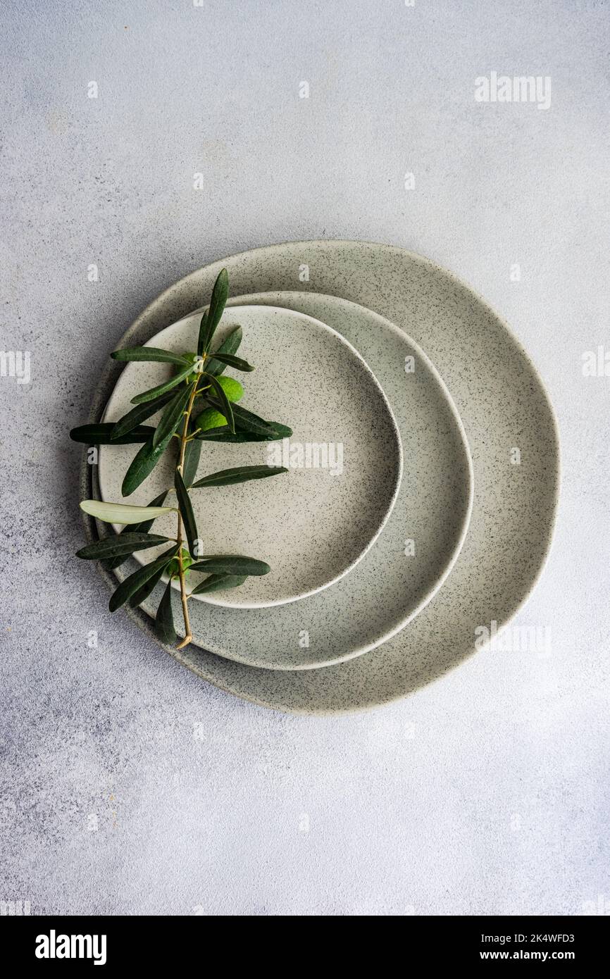 Overhead view of an olive branch on a stack of rustic ceramic plates