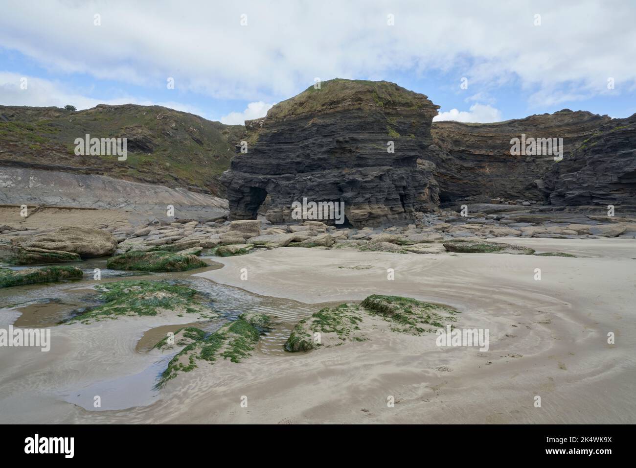 Geological arch with barnacle encrusted rocks in foreground at Broadhaven, Pembrokeshire. Stock Photo