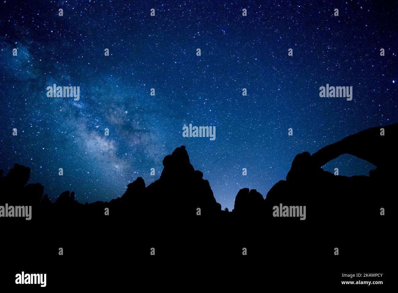 The Milky Way over silhouetted rock formations in Arches National Park, including the South Window.  Moab, Utah. Stock Photo