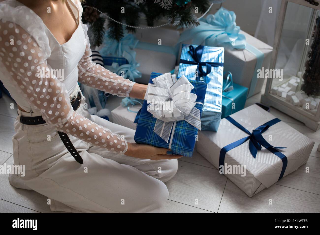 unrecognizable young woman in white clothes on christmas eve at home near many gift boxes. prepare a surprise to dream, a gift with love. Festive atmo Stock Photo