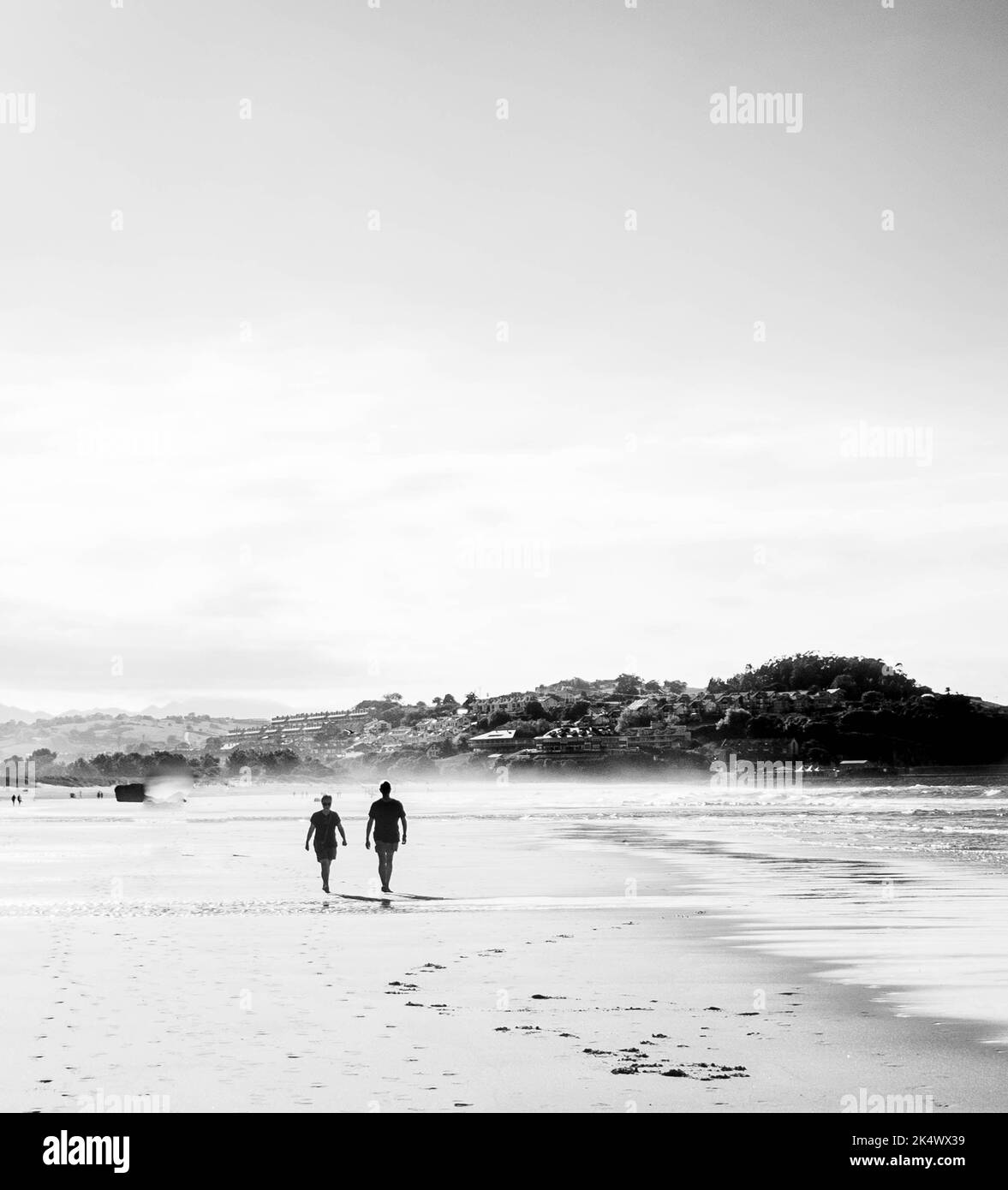 two people walking on the beach at sunset Stock Photo