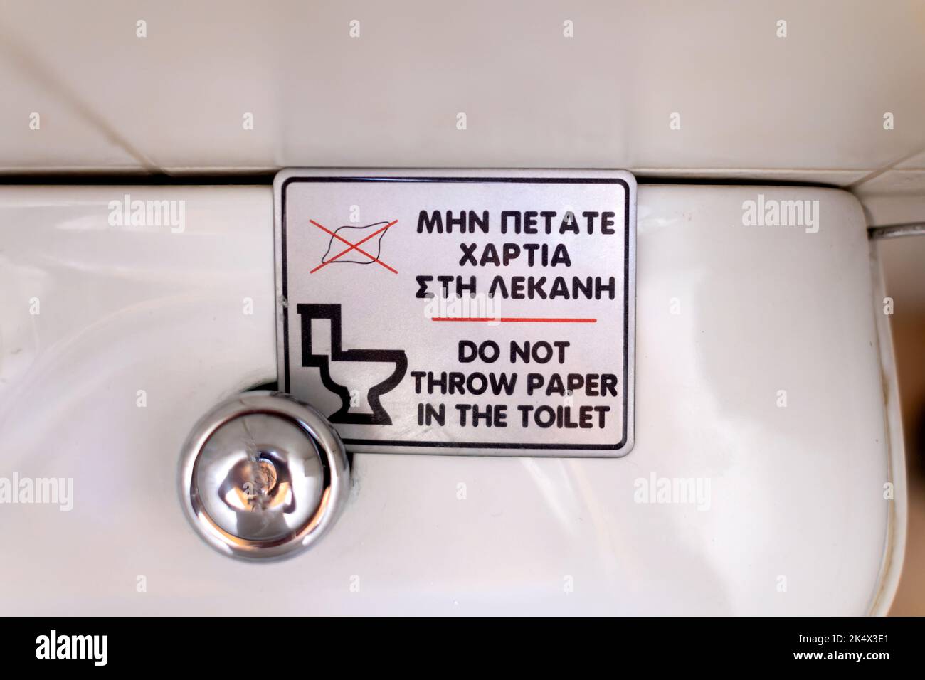 A sign on a Greek toilet cistern asking people who use the toilet not to put any toilet paper used into the toilet. Flushed paper can block pipes Stock Photo