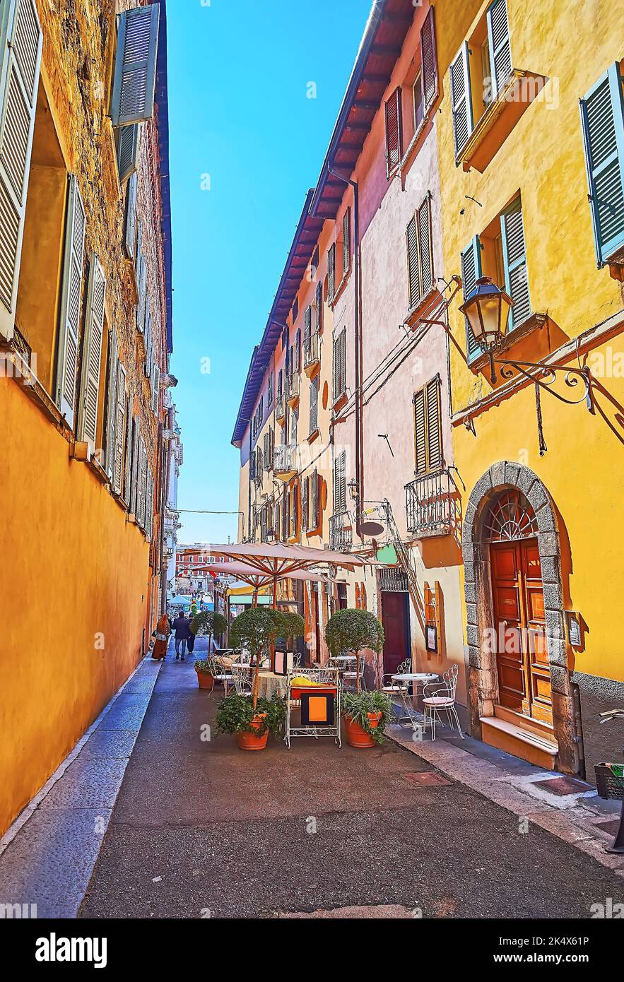 The narrow Vicolo Sant'Agostino street with historic houses and outdoor restaurants with tiny tables, sunshades and plants in pots, Brescia, Italy Stock Photo
