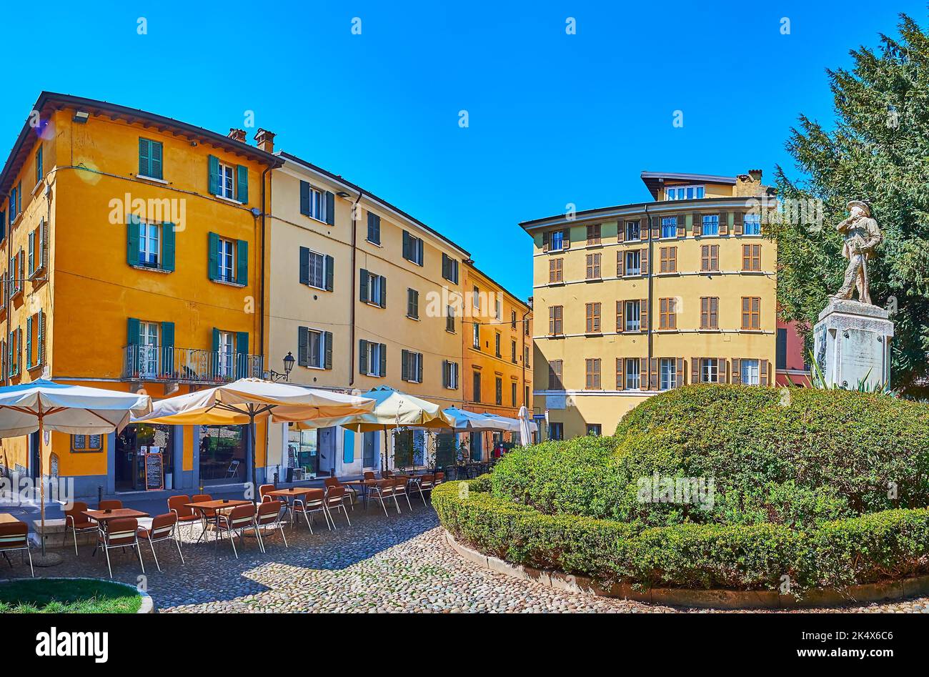 Panorama of historic Piazza Tito Speri Square with historic houses, outdoor cafes, lush green park and monument to Tito Speri, Brescia, Italy Stock Photo