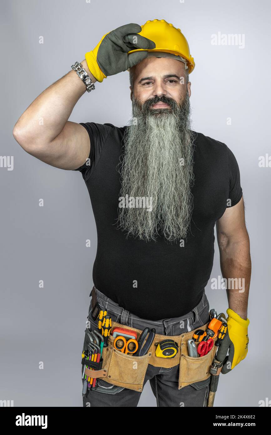 worker with tool belt greets getting up his helmet Stock Photo