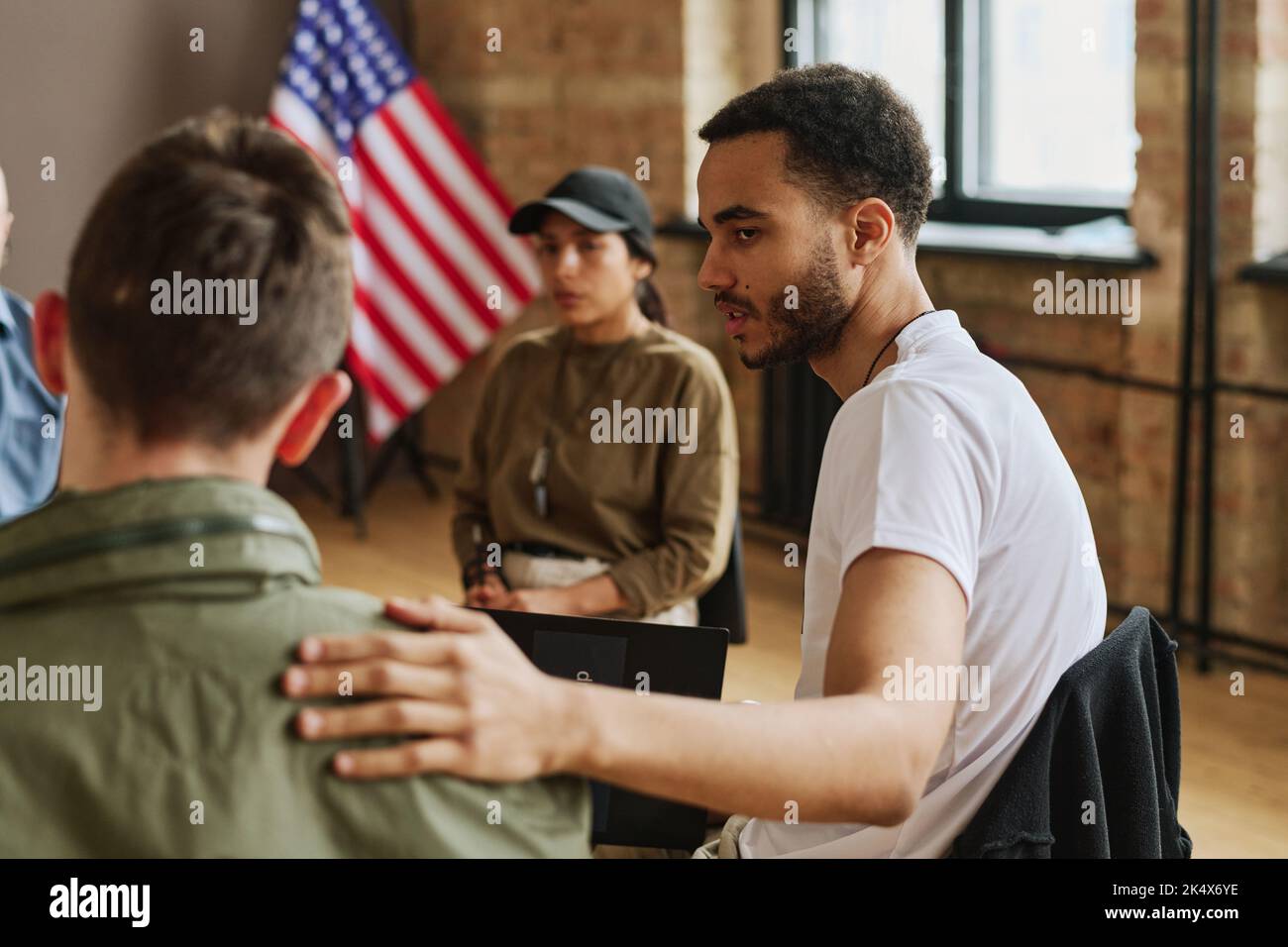 Young multi-ethnic man supporting depressed guy while keeping hand on ...