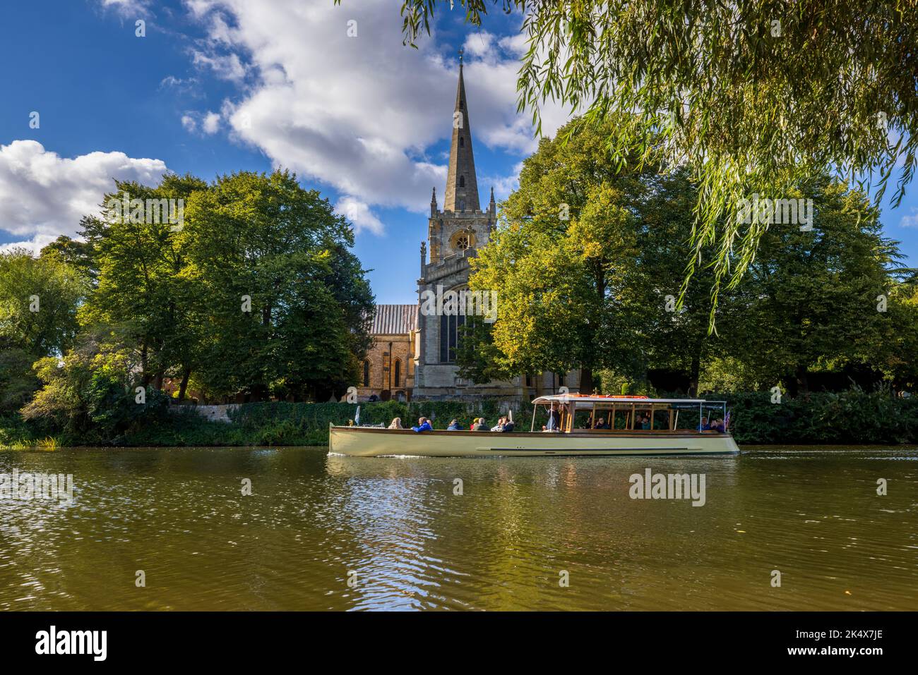 A River Cruise boat passing Holy Trinity church at Stratford upon Avon, Warwickshire, England Stock Photo