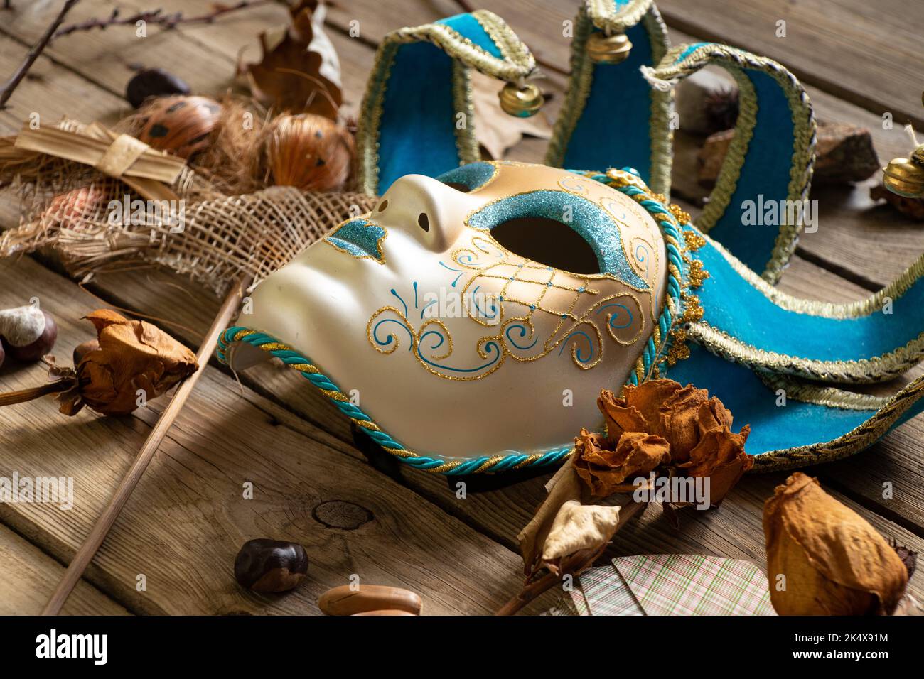 The Venetian mask lies on a wooden table with feather cards and voodoo dolls and shamanic items, mystery and mysticism Stock Photo