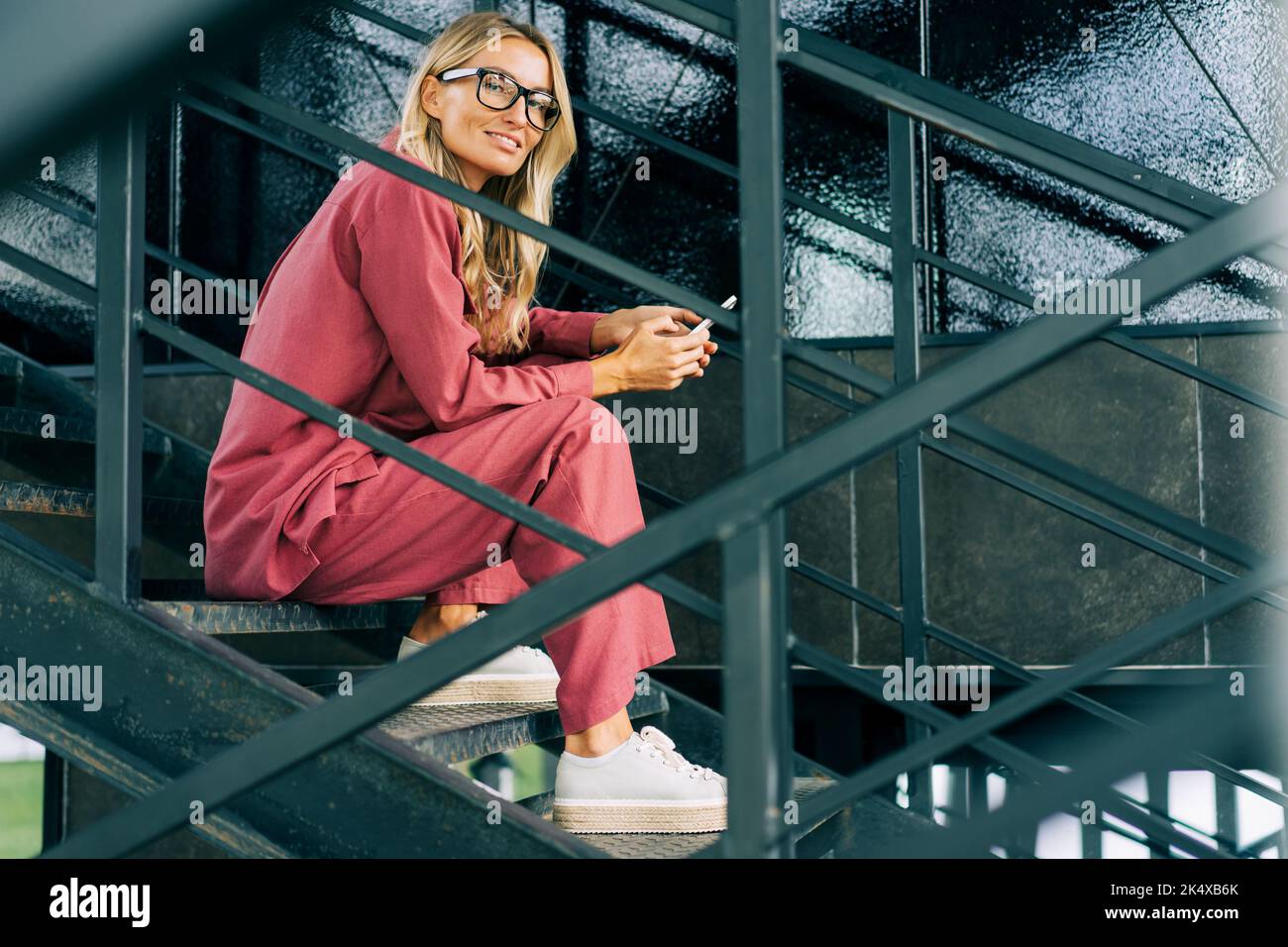 Portrait of a young business woman sitting on a step and using the phone. Stock Photo