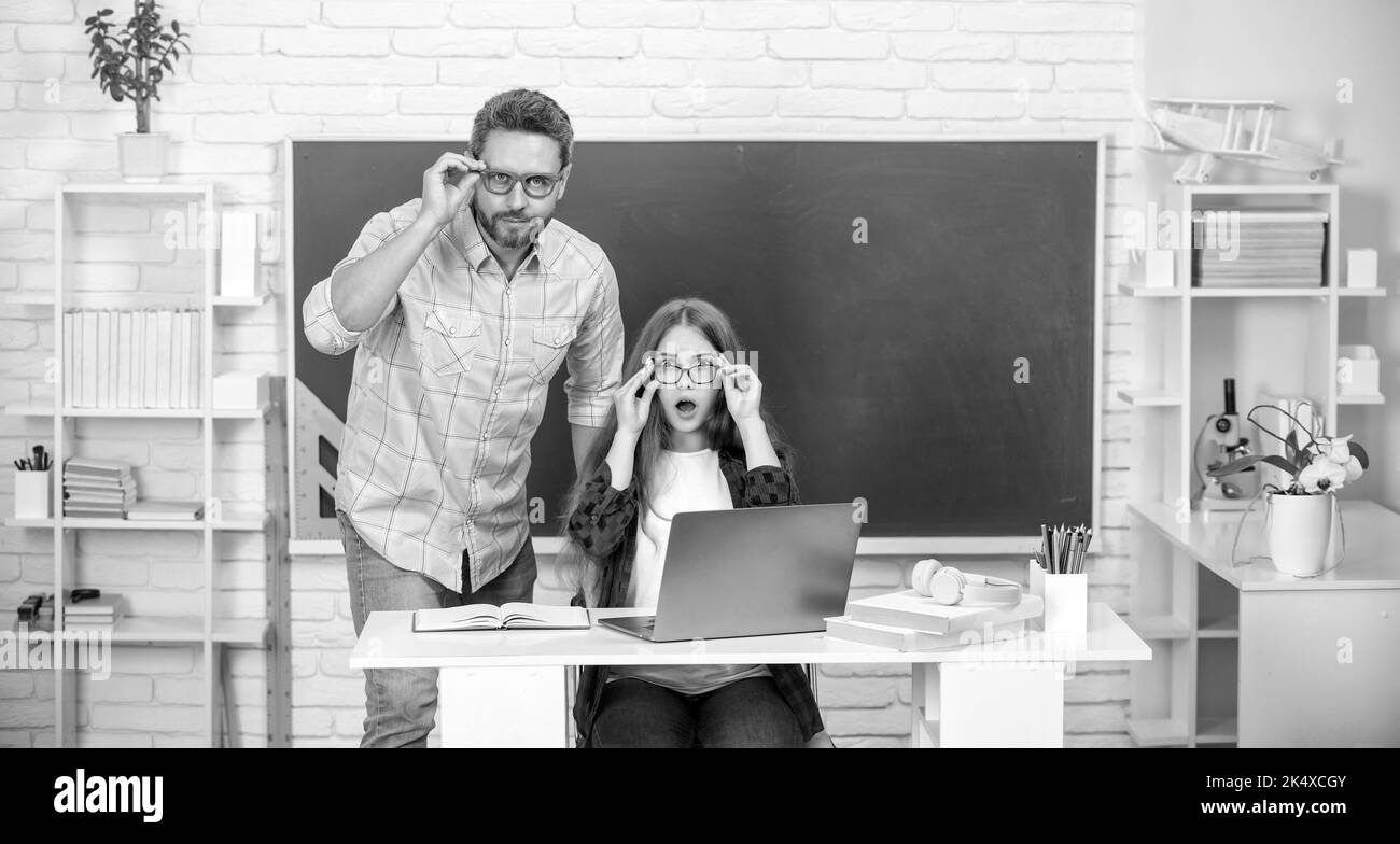 surprised teen girl and teacher man in high school with pc at blackboard, e-learning Stock Photo