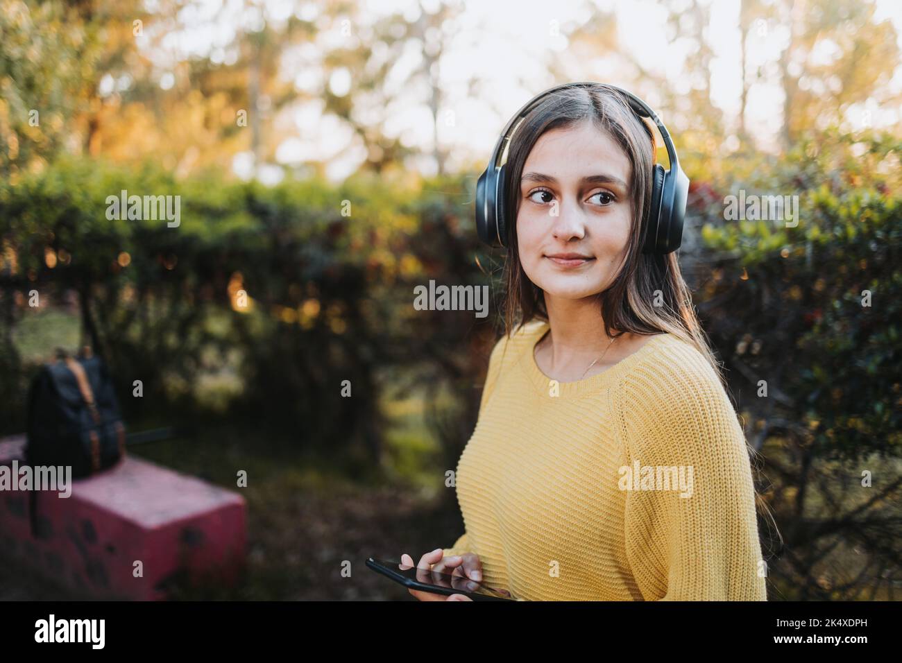 Smiling serene female university student using her laptop in campus natural park. E-learning concept. Stock Photo