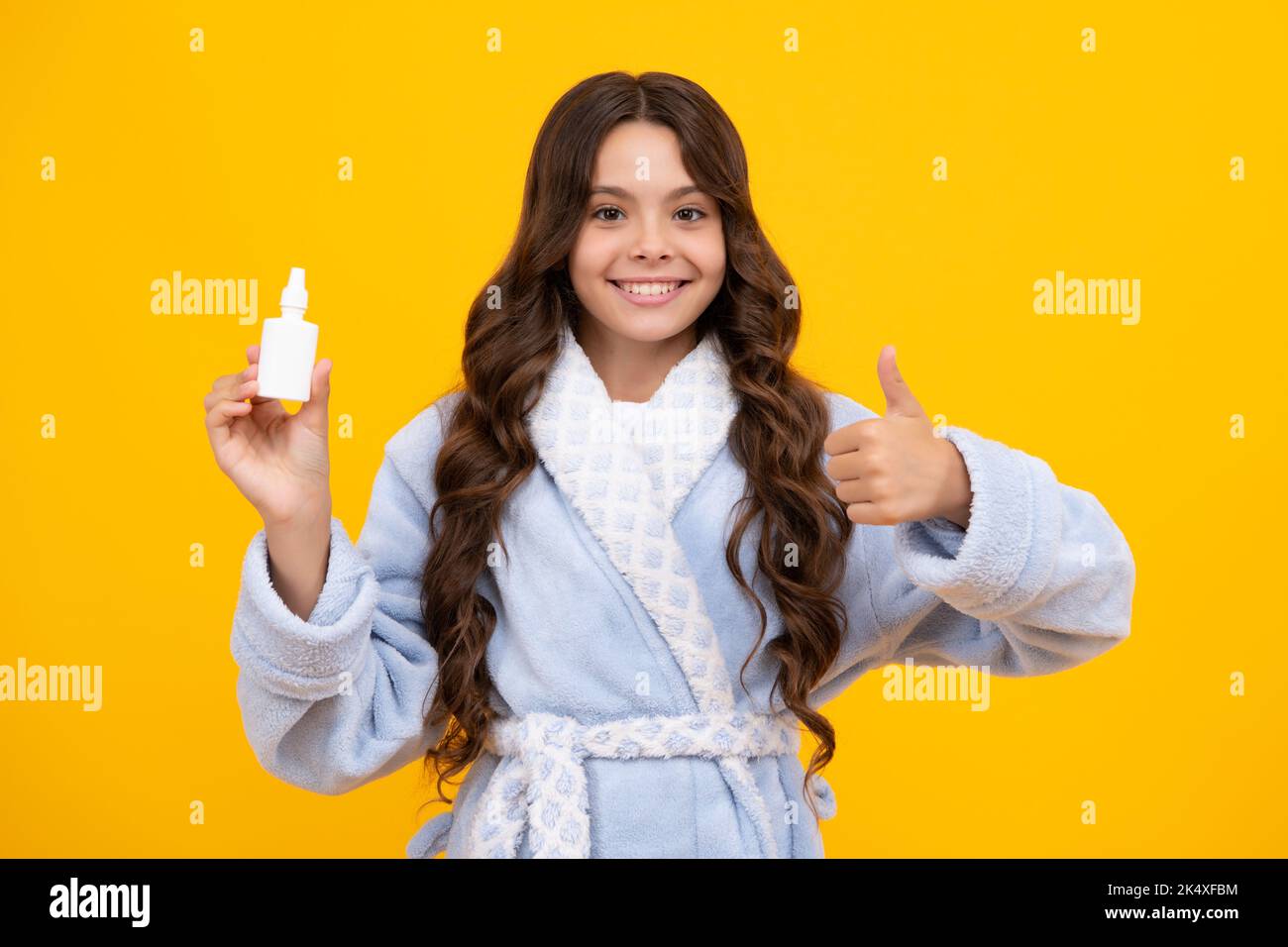 Tunny nose and allergy, nasal spray. Teen girl in pajama use nasal drops, stuffed nose isolated on yellow background. Stock Photo