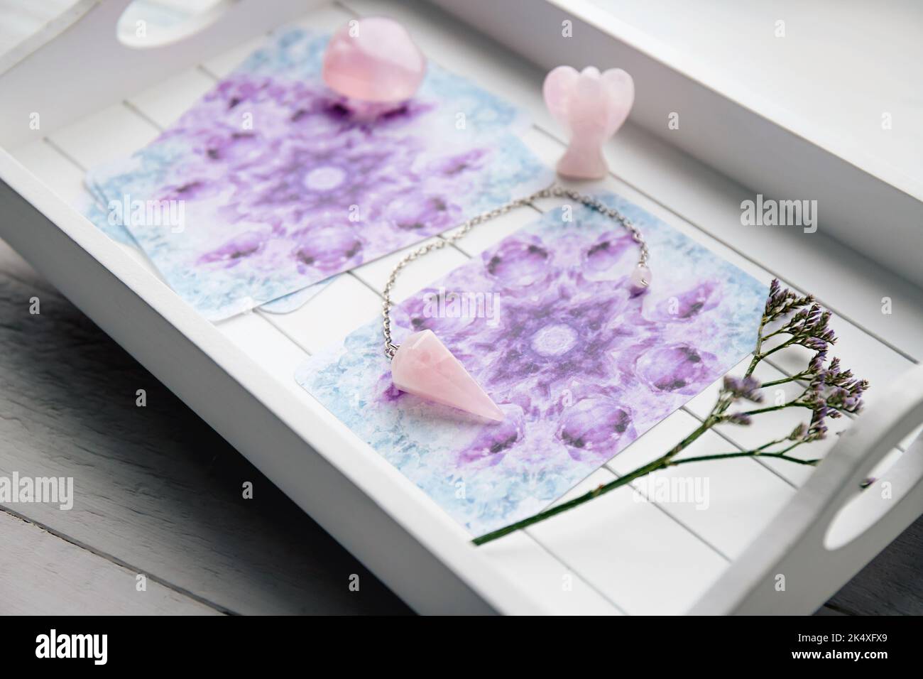 Deck with homemade Angel cards on white tray at home table, surrounded with semi precious stones rose quartz crystals and angel shape figurine. Stock Photo