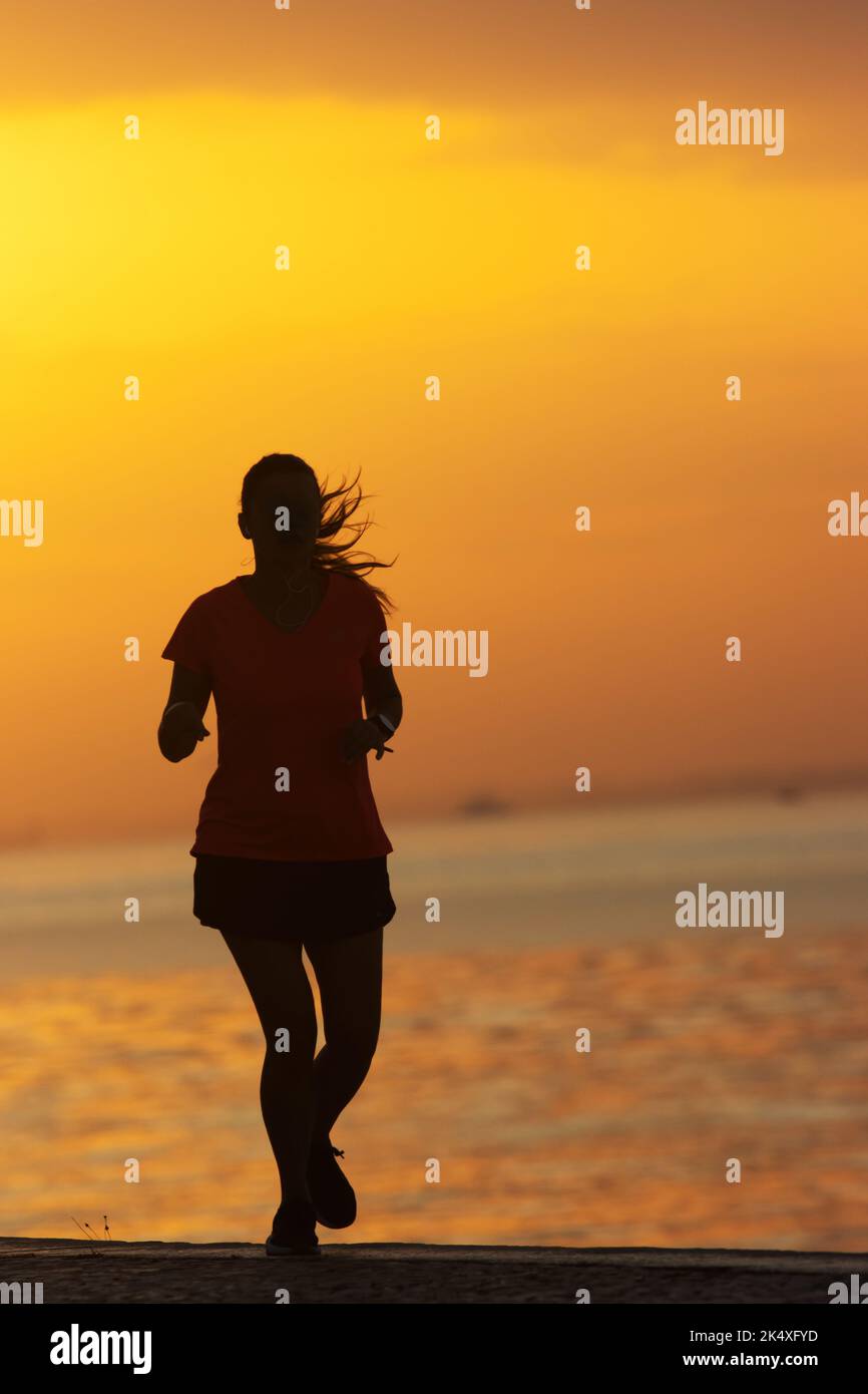 Silhouette of young woman are exercising running on the river. Healthy running and outdoor jogging Stock Photo