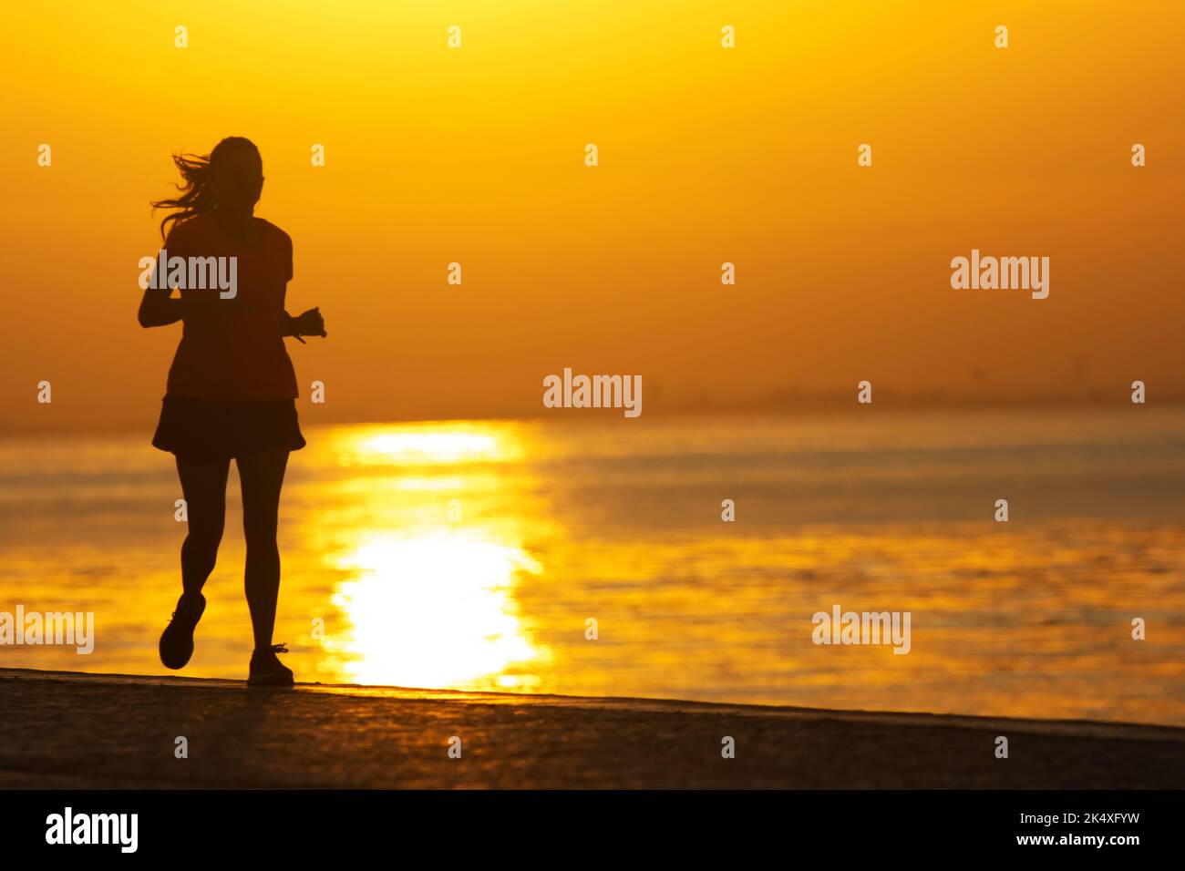 Silhouette of young sportive woman are running on the river. Healthy running and outdoor exercise Stock Photo
