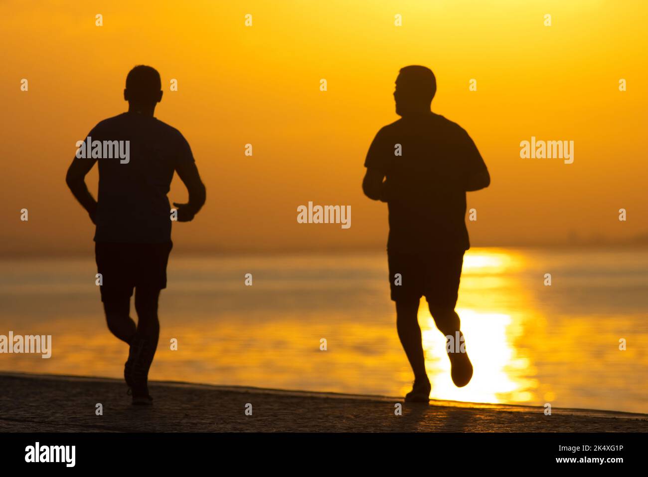 The two men running at the sunrise on river coast Stock Photo