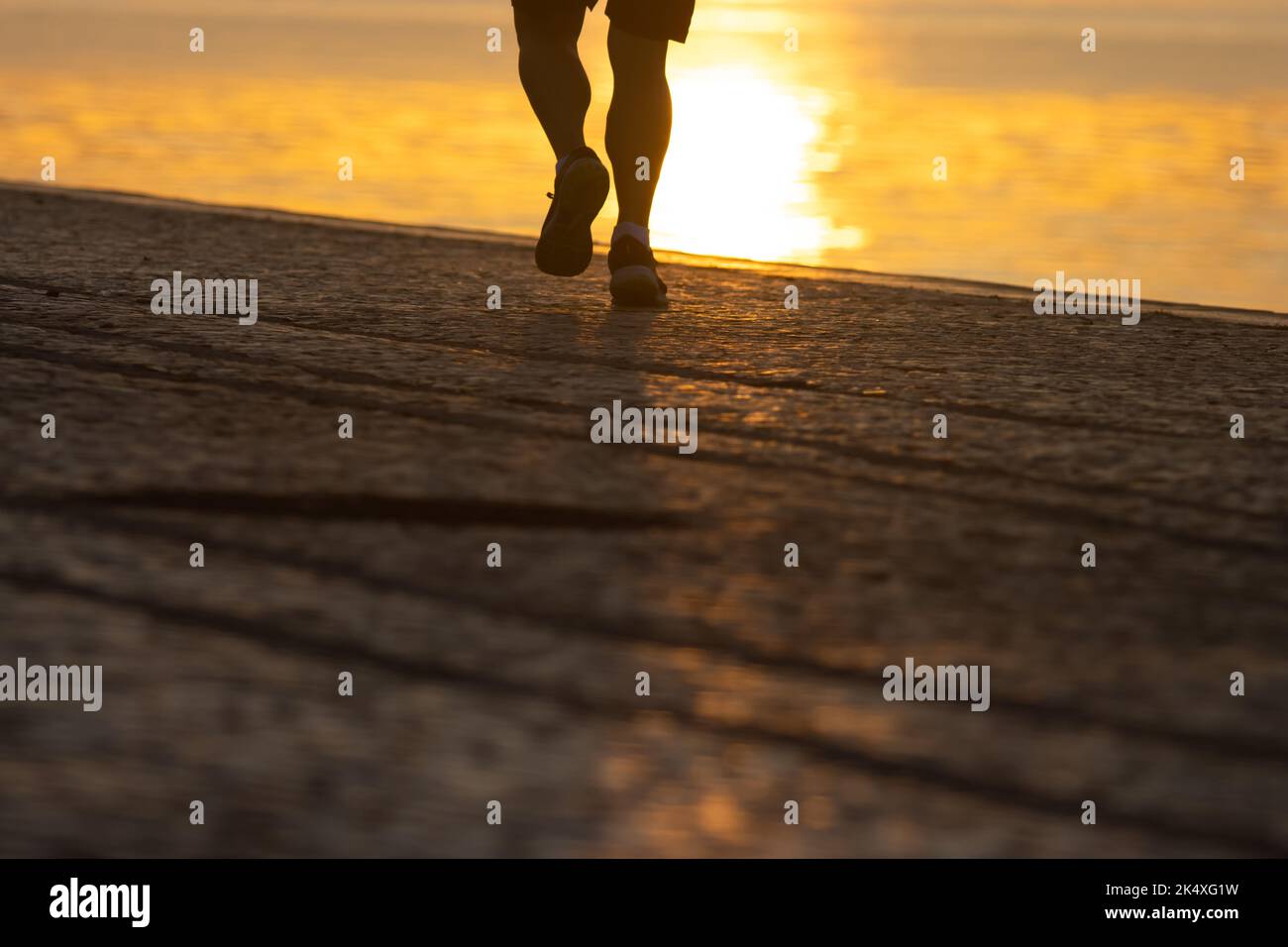 Silhouette of legs athlete running at the sunrise on river coast Stock Photo