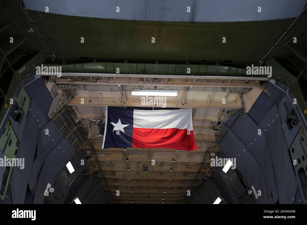 Texas flag in the military cargo airplane and aircraft. Wavy flag is lit by light. Detail of mechanics and national symbol. Stock Photo