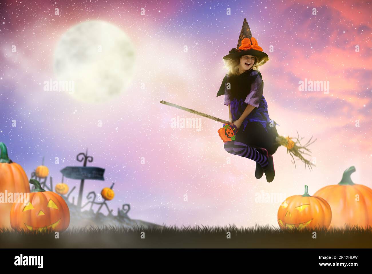 Little witch flying broom on Halloween night. Huge full moon and bats ...