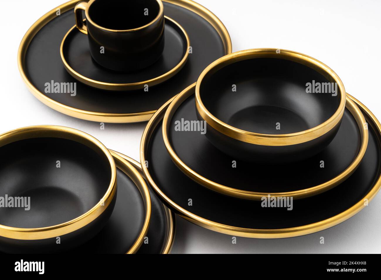 A Set of black and golden ceramic plates and cup on a white background Stock Photo