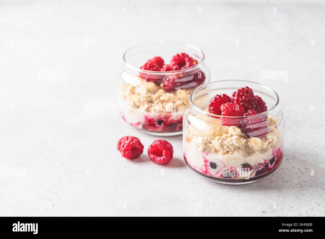 Overnight oatmeal with raspberries, currants and tahini in jars, copy space. Healthy breakfast concept. Stock Photo