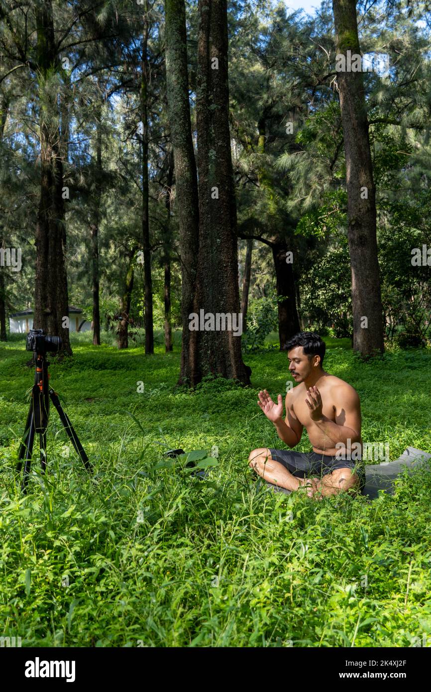View of a man conducting virtual fitness class with group of people at home on a video conference. Fitness instructor taking online yoga classes Stock Photo