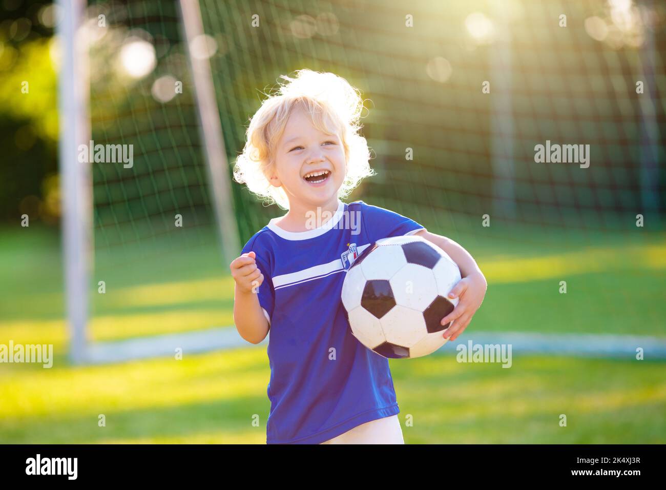 Kids play football on outdoor field. France team fans with national