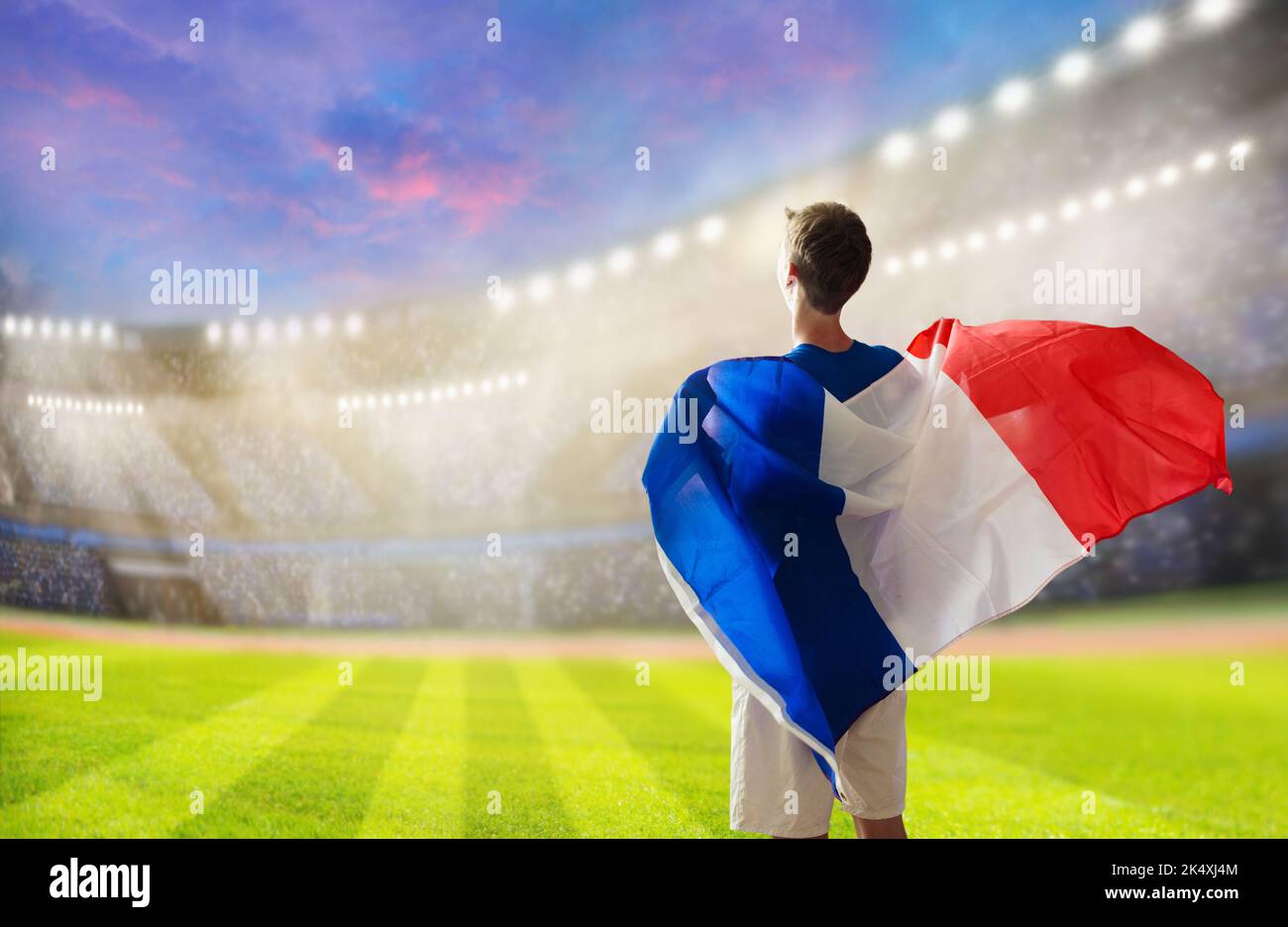 France football supporter on stadium. French fan on soccer pitch watching team play. Young player with flag and national jersey cheering for France. Stock Photo