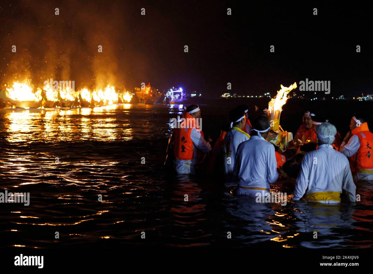 Devotees carry a flaming urn into the sea in a ritual to send off the gods during the last day of the Taoist Nine Emperor Gods festival in Singapore October 4, 2022. REUTERS/Edgar Su Stock Photo
