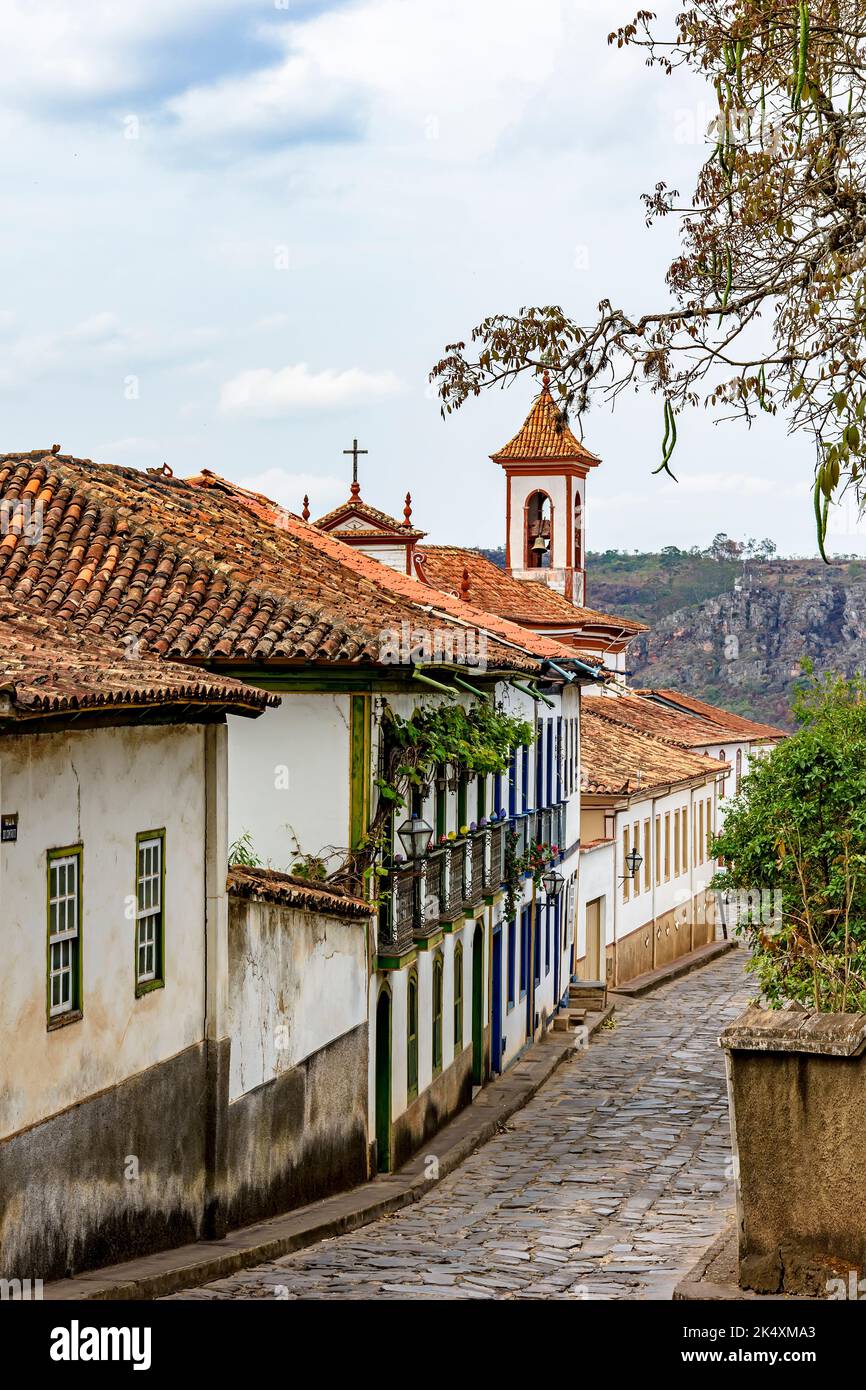 Cobbled street in the city of Diamantina with its colonial-style houses and colorful balconies with the church bell tower in the background Stock Photo