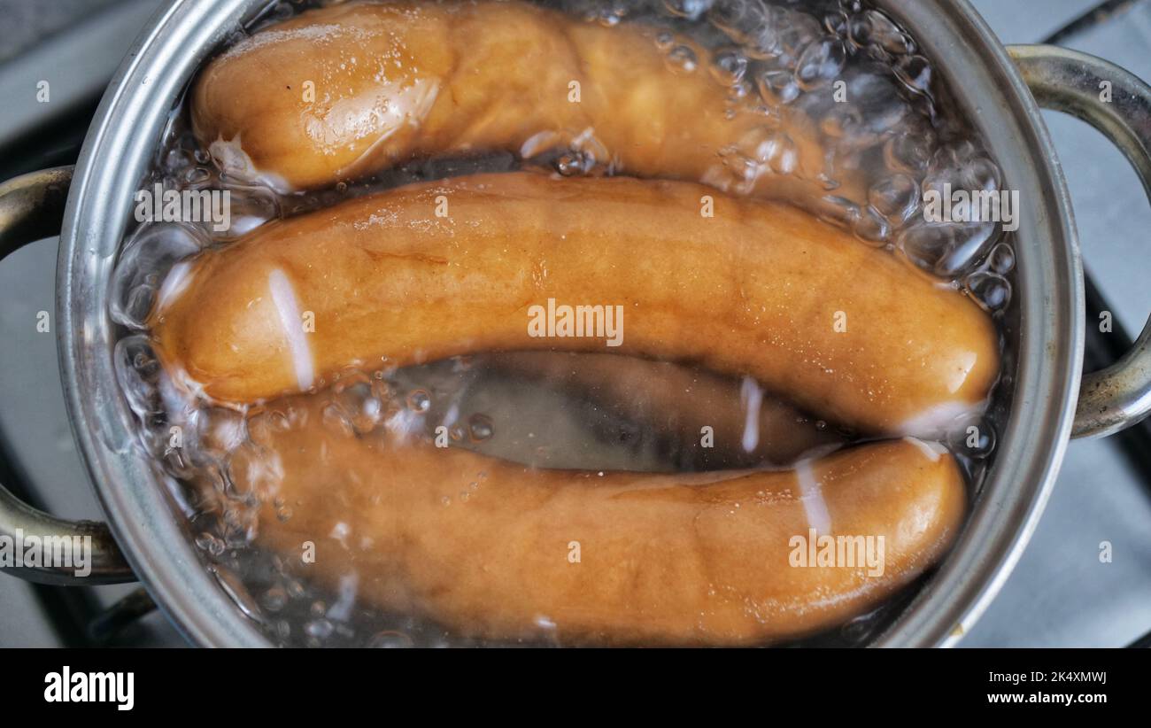 sausages are cooked in a pot with boiling water. We cook at home on a gas stove. Stock Photo