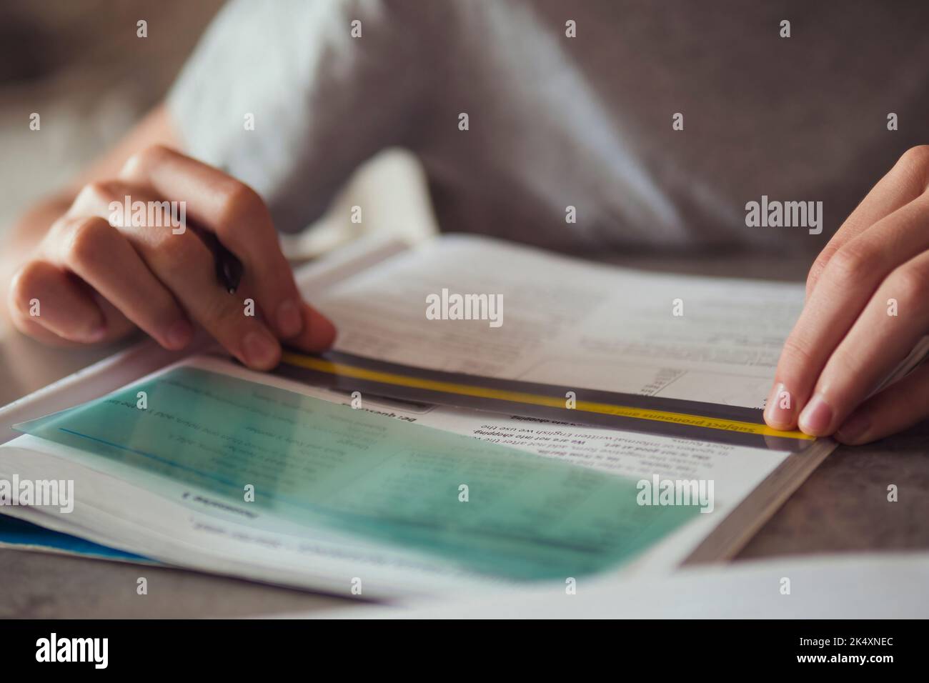 Kid affected by dyslexia doing homework, writing, reading notebook task using colorful overlay