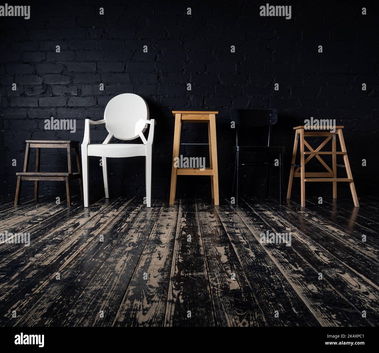 A row of five empty modern chairs in front of a stylish brick wall