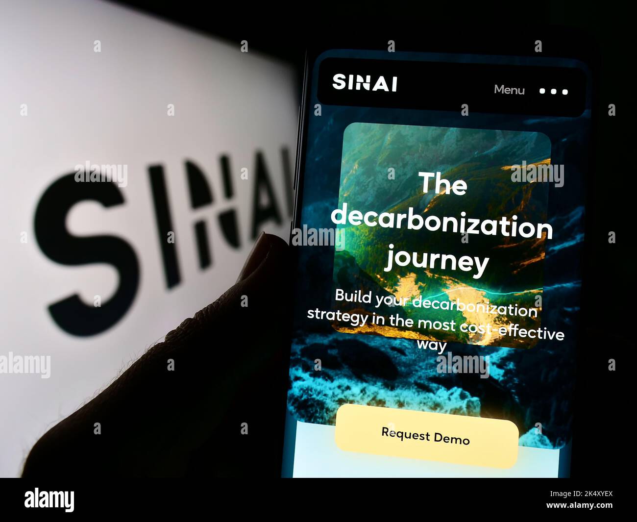 Person holding cellphone with webpage of US decarbonization company SINAI Technologies Inc. on screen with logo. Focus on center of phone display. Stock Photo