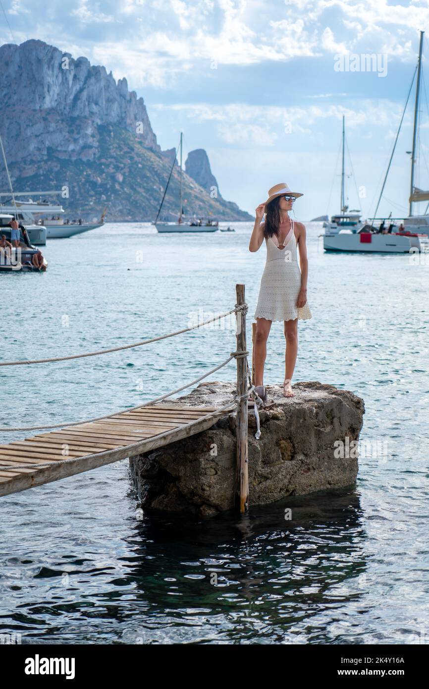 Brunette woman with hat and light beige dress on Ibiza pier Stock Photo
