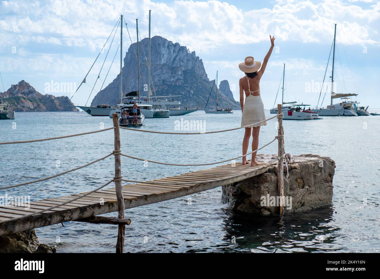 Brunette woman with hat and light beige dress on Ibiza pier Stock Photo