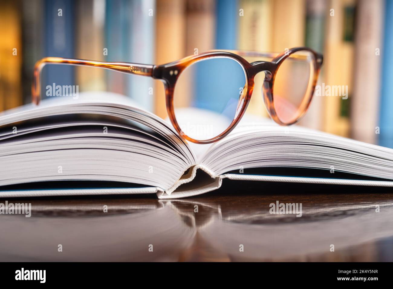 Closeup of reading glasses lying on opened book in library Stock Photo